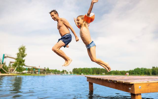 Vater und Kind springen in einen See